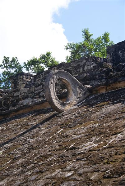 Maya stone ballgame ring atop a ruined pyramid under blue sky