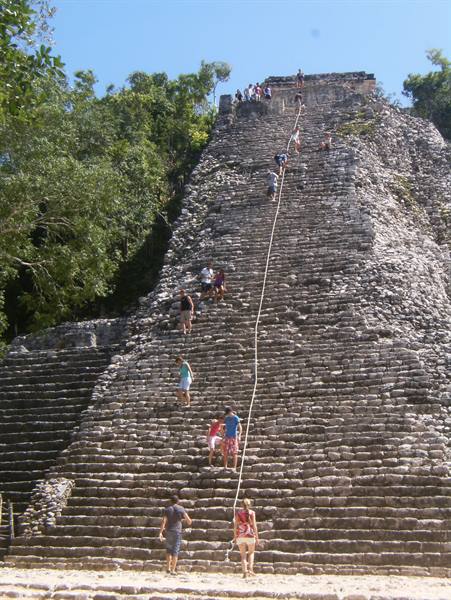 Tourists climbing the great stone pyramid at Cobá under the sun