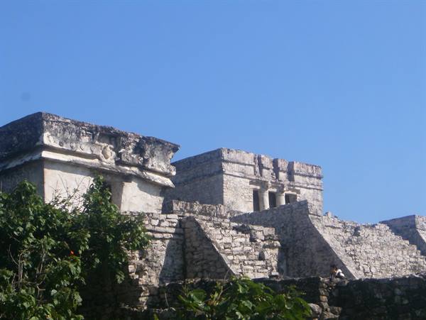 Mayan stone ruins at Tulum, blue sky and green vegetation