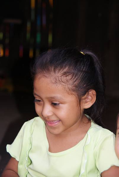 Smiling girl with ponytail, green t-shirt, soft indoor light