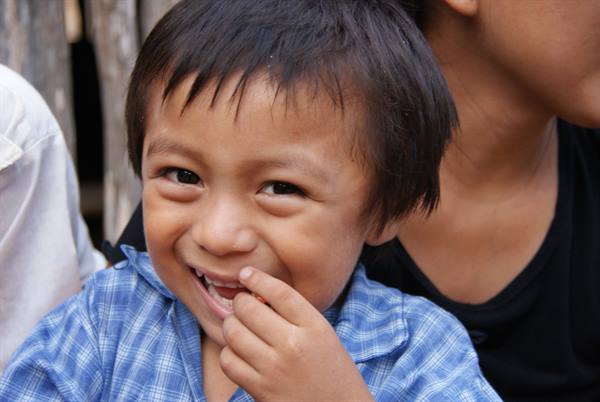 Smiling child in checkered shirt, finger in mouth