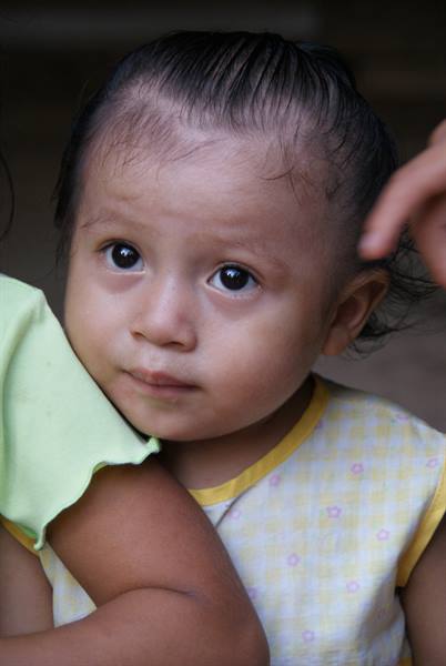 Little girl with big dark eyes in a yellow shirt held close