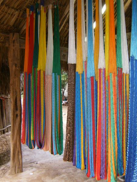 Colorful hammocks hanging under a thatched roof at a craft market