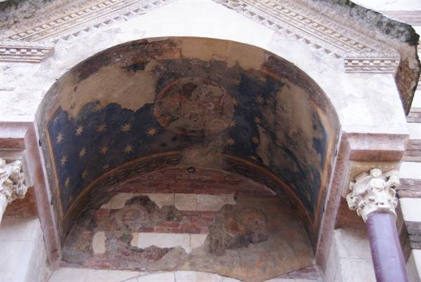 Golden stars on blue mosaic inside a weathered arch, marble columns beside