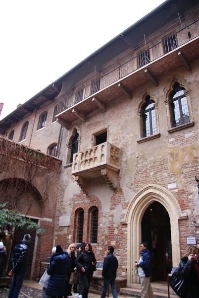 Tourists in the courtyard of Juliet's House in Verona with marble balcony