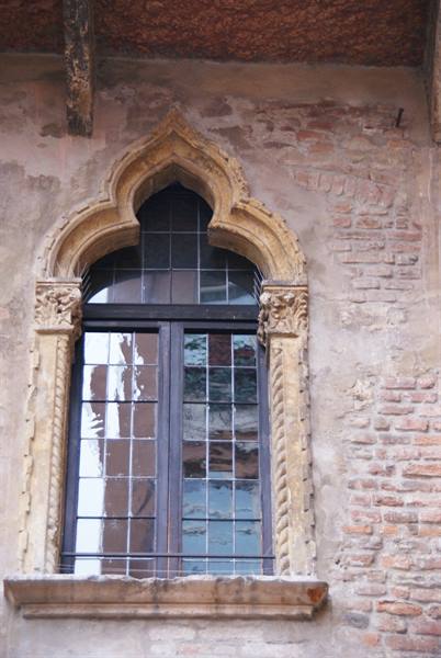 Venetian Gothic stone window set in an old brick wall