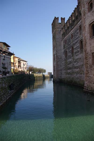 Scaligero Castle in Sirmione reflects in the green moat water