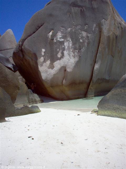 Huge granite boulders over white sand beach, turquoise water, clear blue sky