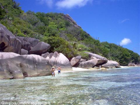 Tourists wading in clear water among huge granite boulders, Anse Source d'Argent beach