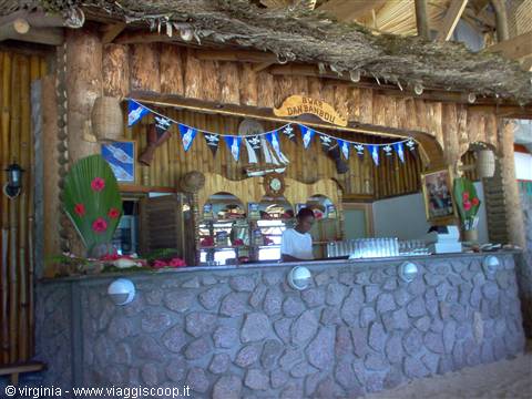 Wooden thatched bar with stone counter, blue flags, bartender working