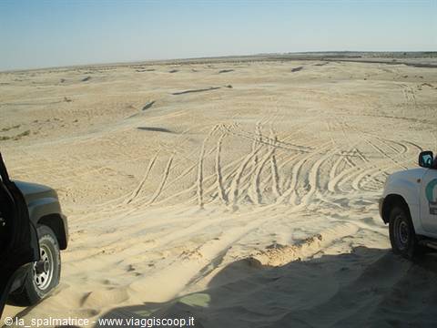 Two SUVs on sand dunes with tire tracks