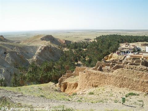 Mud brick ruins overlooking a palm oasis in the Tunisian desert