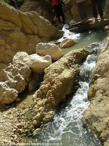 Hikers among limestone rocks along a fast-flowing stream