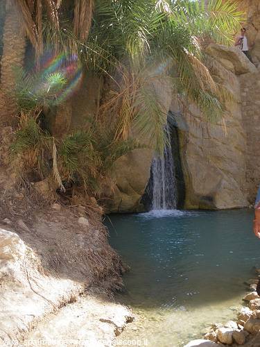 Small waterfall in Chebika oasis, rock and palms, turquoise water