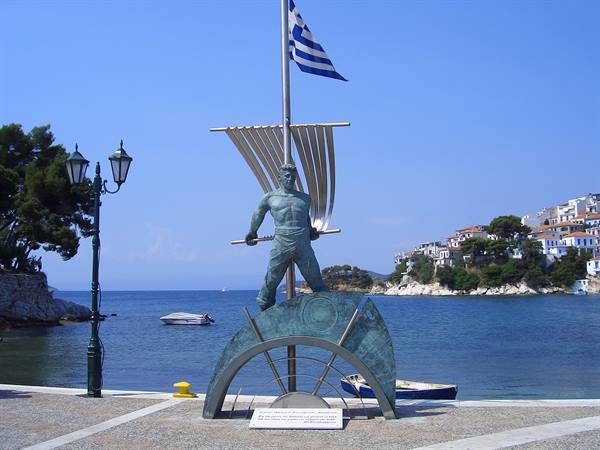 Bronze sailor statue with Greek flag at Skiathos harbor