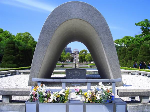 Hiroshima Cenotaph with floral offerings, Atomic Bomb Dome in the background