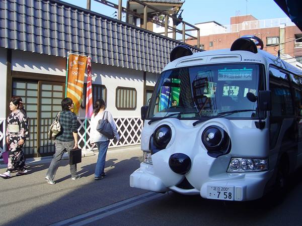 White panda bus parked by a temple, pedestrians in kimono at Asakusa
