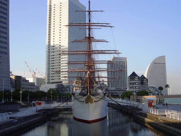 Nippon Maru sailing ship moored in dry dock before Yokohama skyscrapers