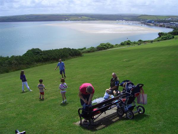 Family playing on the lawn, bench and stroller, bay with sandbank and boats