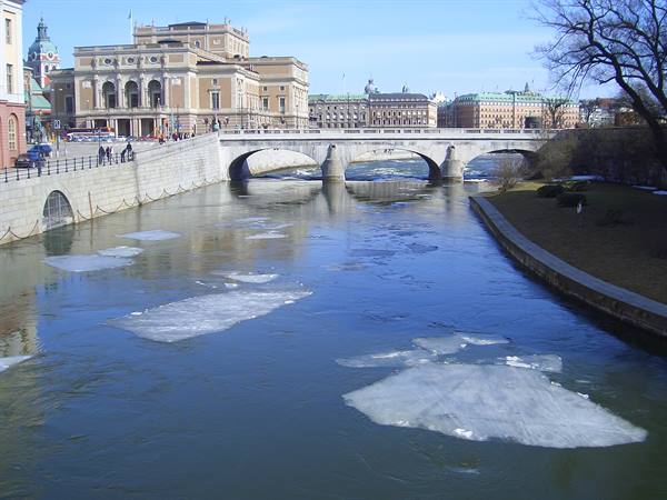 Stone bridge in Stockholm with floating ice sheets, opera house behind