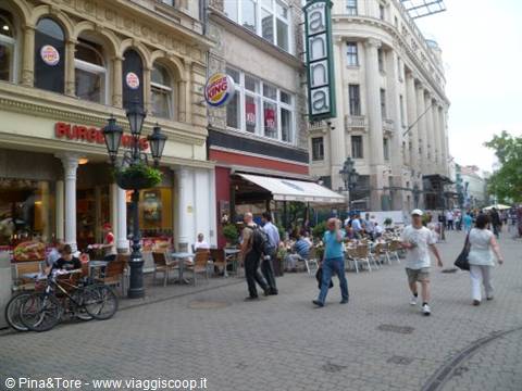 Pedestrians strolling past a Burger King and outdoor café, Anna sign
