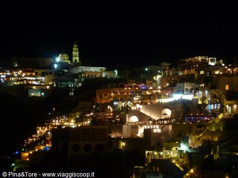 Fira at night: lit whitewashed houses on the caldera and bell tower