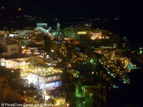 Fira at night: illuminated white houses on the caldera, domes and golden lights