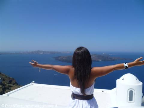 Woman in white with open arms facing the Aegean sea, Imerovigli