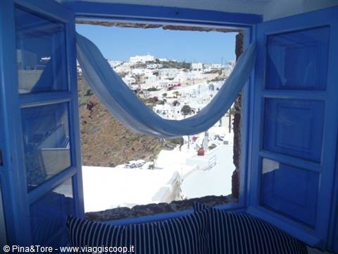 Blue window with cloth framing the white houses of Oia