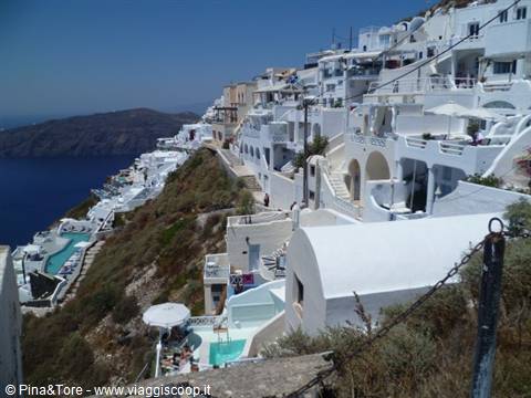Whitewashed cave houses on Fira caldera cliff, blue pools below