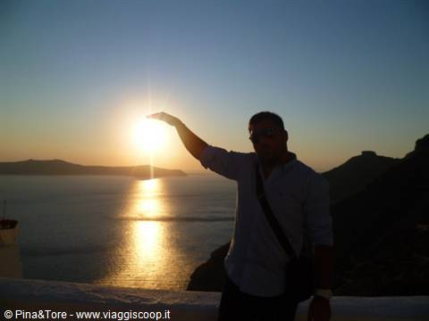 Man touches the sun with his hand over Oia caldera, Santorini