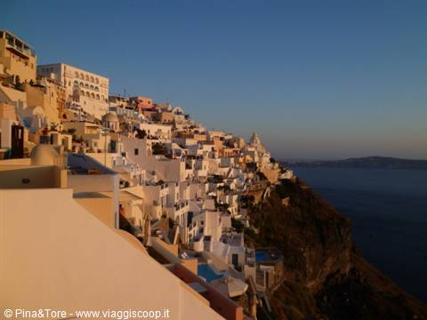 White houses carved into Fira's caldera cliff in morning light