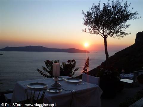 Set table on a Santorini terrace as the sun sinks into the sea