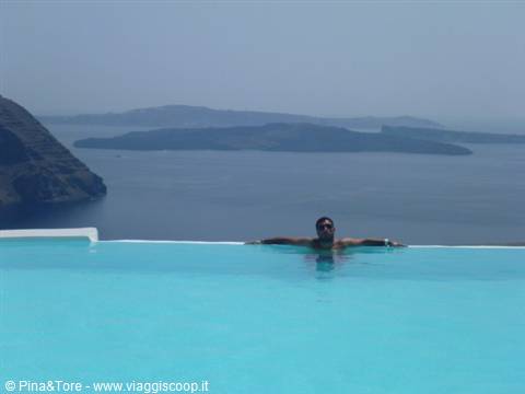Man in infinity pool over the Thira caldera, turquoise water and volcanic islands