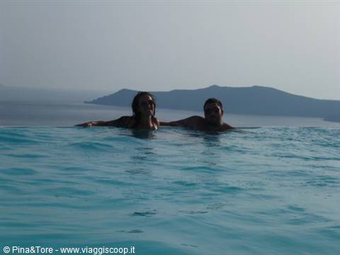 Couple swimming in an infinity pool above the Aegean Sea, Santorini