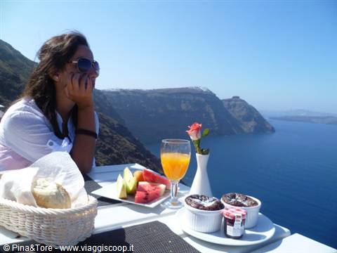 Breakfast with fruit and orange juice on a white terrace in Oia, Santorini