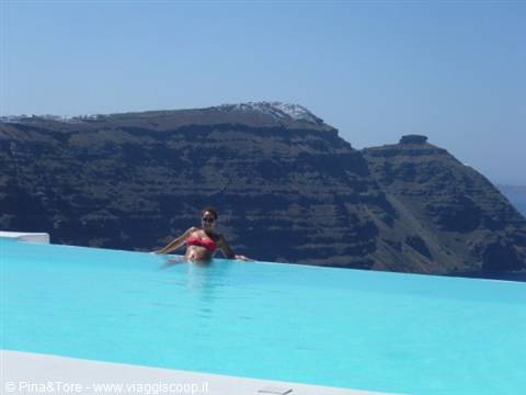Woman in infinity pool before Santorini caldera cliffs