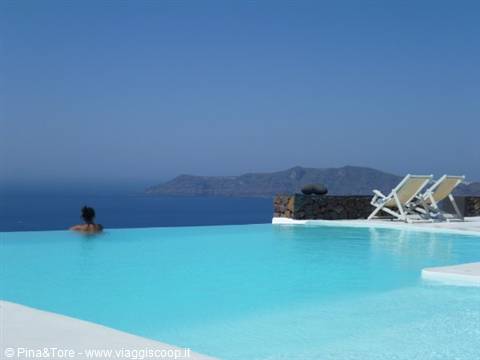 Infinity pool in Imerovigli, woman in turquoise water, loungers facing the caldera