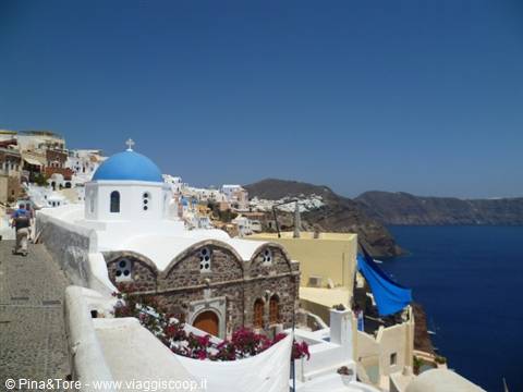Blue-domed church among whitewashed houses and bougainvillea in Oia