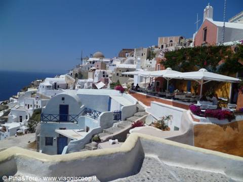 White houses and church in Oia, white umbrellas above the Aegean Sea