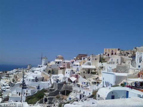 Oia: whitewashed cliff houses and windmill under blue sky