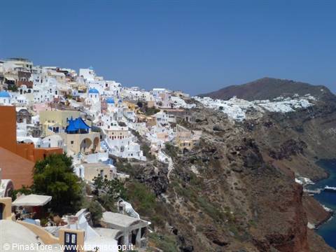 White and blue houses of Oia carved into the caldera, clear sky