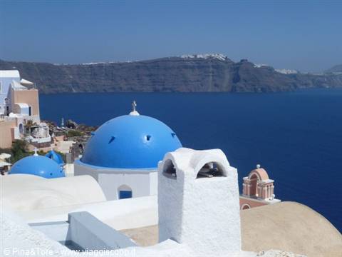 Blue church domes and white houses in Oia above the Aegean Sea