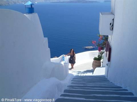 Woman on white and blue staircase leading to the sea in Oia