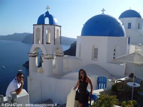 Tourists beside white churches with blue domes in Oia, Santorini