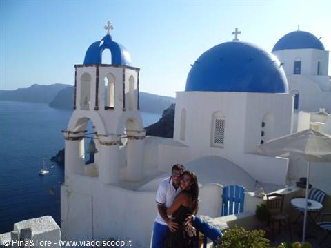Oia, Santorini: couple embracing before white churches with blue domes