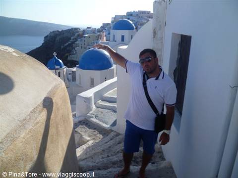 Tourist pointing at the blue-domed churches of Oia among white houses by the sea