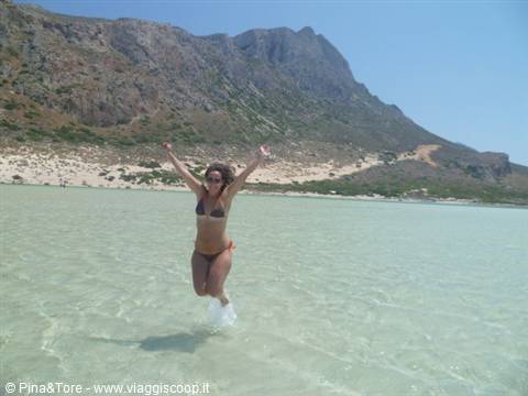 Woman in bikini jumps joyfully in the turquoise water of Balos lagoon, Crete