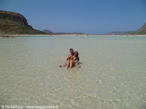Couple sitting in the shallow turquoise water of Balos lagoon, Crete