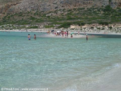 Bathers in the turquoise Balos lagoon, white sand and dry hills behind
